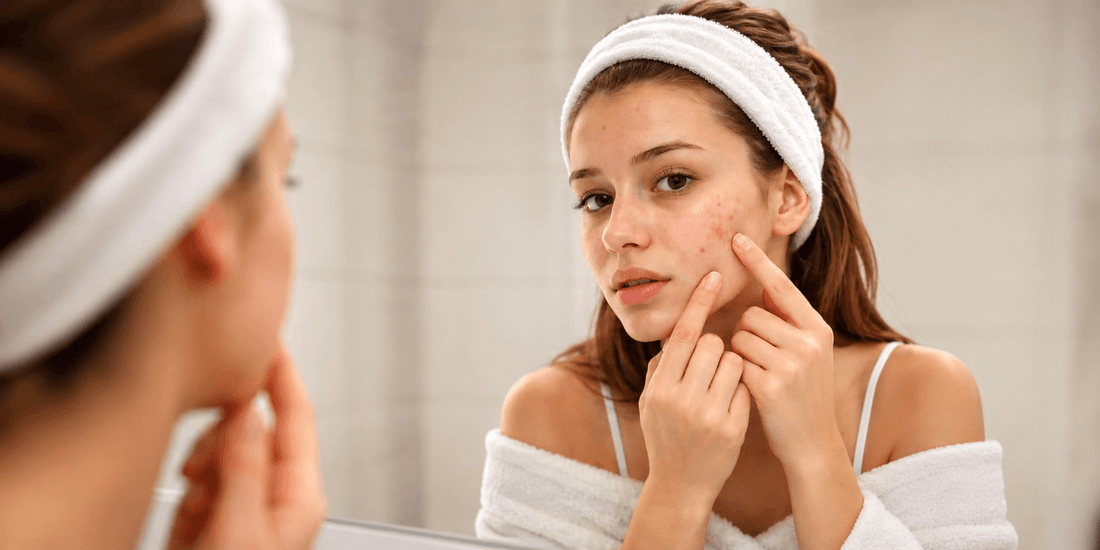 Young woman checking acne-prone skin in the mirror for a skincare and tea tree oil acne treatment